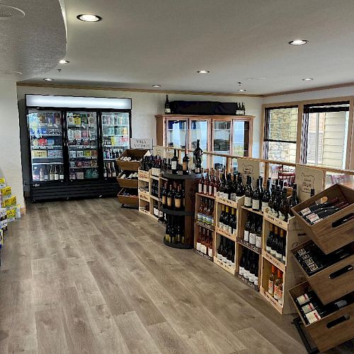 The image shows the interior of a liquor store with bottled beverages on racks and refrigerators. The floor is wooden, and there are windows.