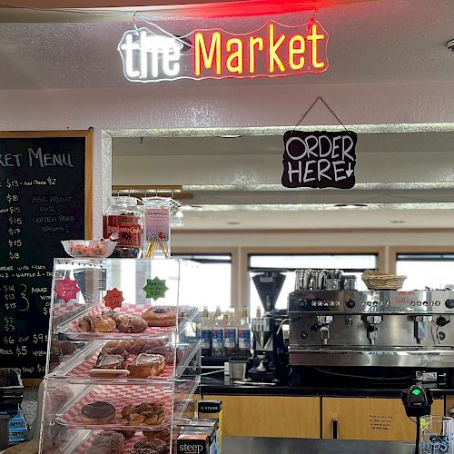 The image shows a coffee shop counter with a menu board, pastries, and a 