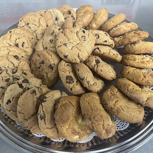 A silver tray with a variety of cookies, including chocolate chip and plain, arranged in a circular pattern.