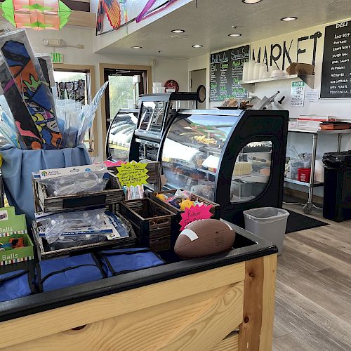 The image shows a small market shop interior with display cases, various items for sale, and a menu board on the wall ending the sentence.