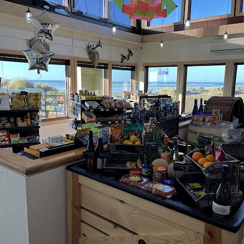 A small store with food, beverages, and snacks, overlooking a scenic outdoor view through large windows.